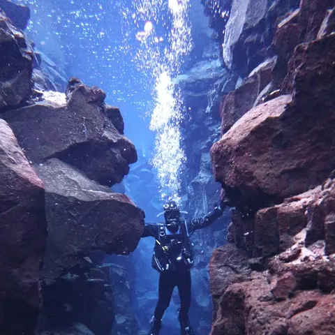A diver standing between the rock walls of the fissure