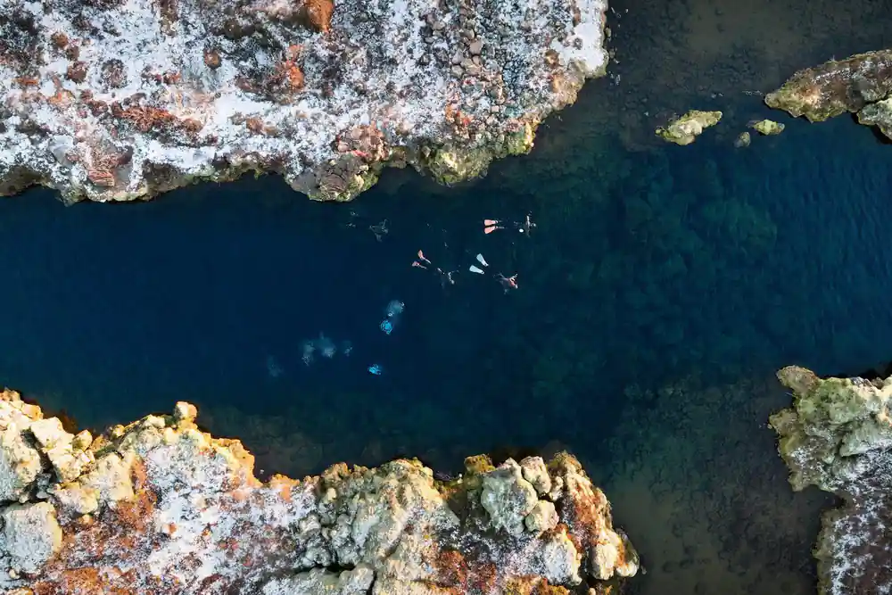 Aerial view of swimmers in narrow water channel between rocks