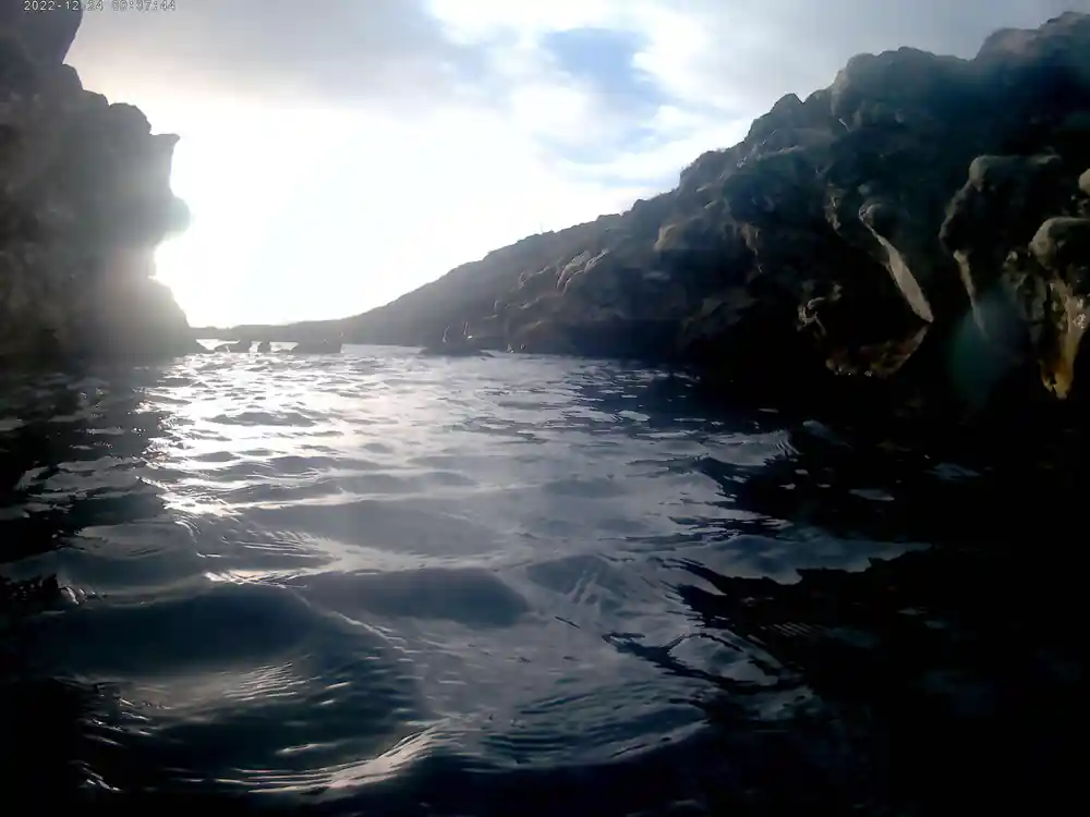 Black rocky cliffs and dark water between steep canyon walls