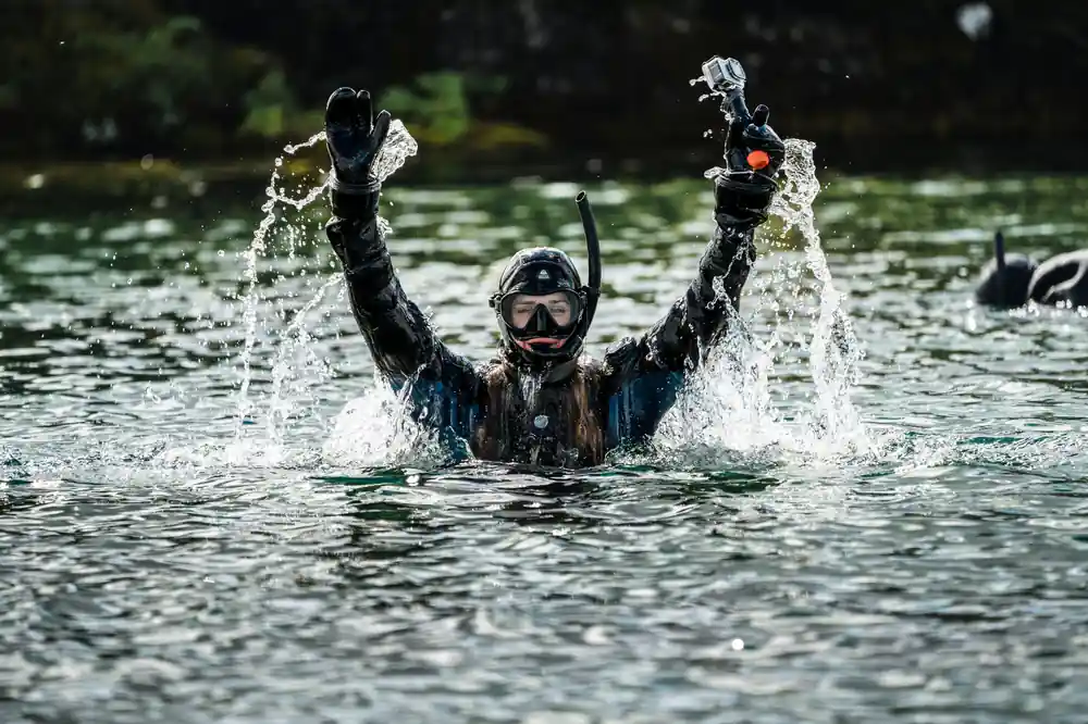 Diver emerging from water with arms raised triumphantly