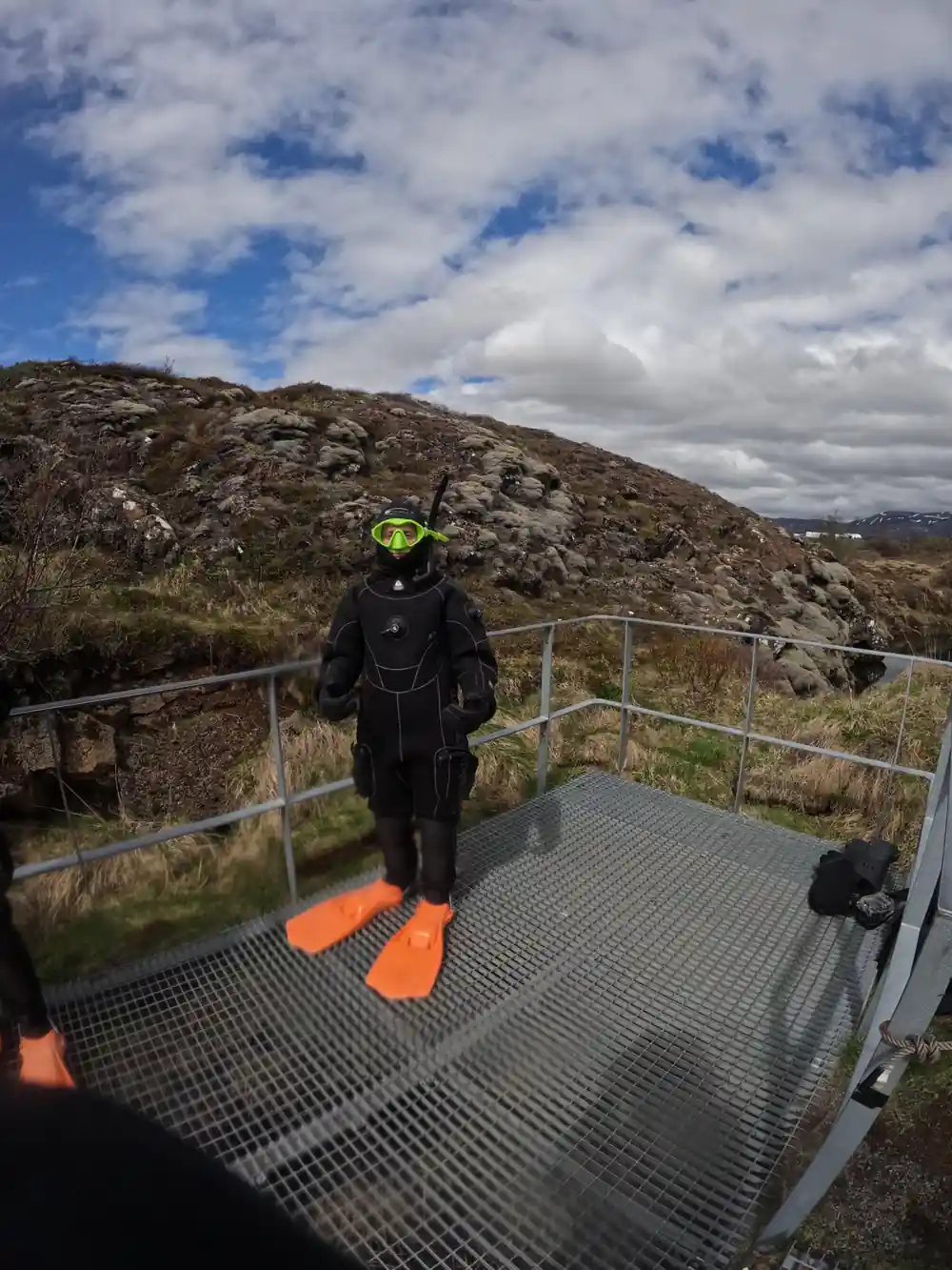 Diver in full gear standing on platform overlooking mountains