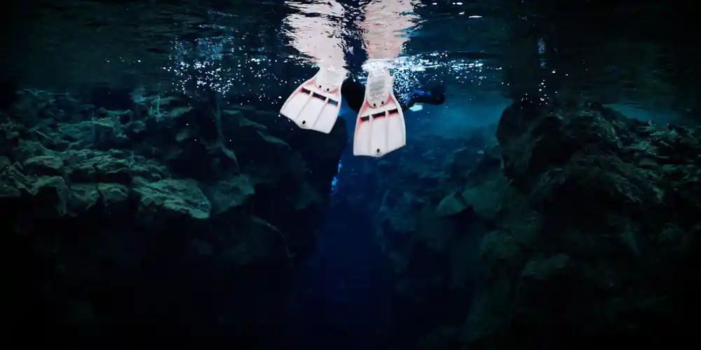 Diver in underwater canyon viewed from above looking up