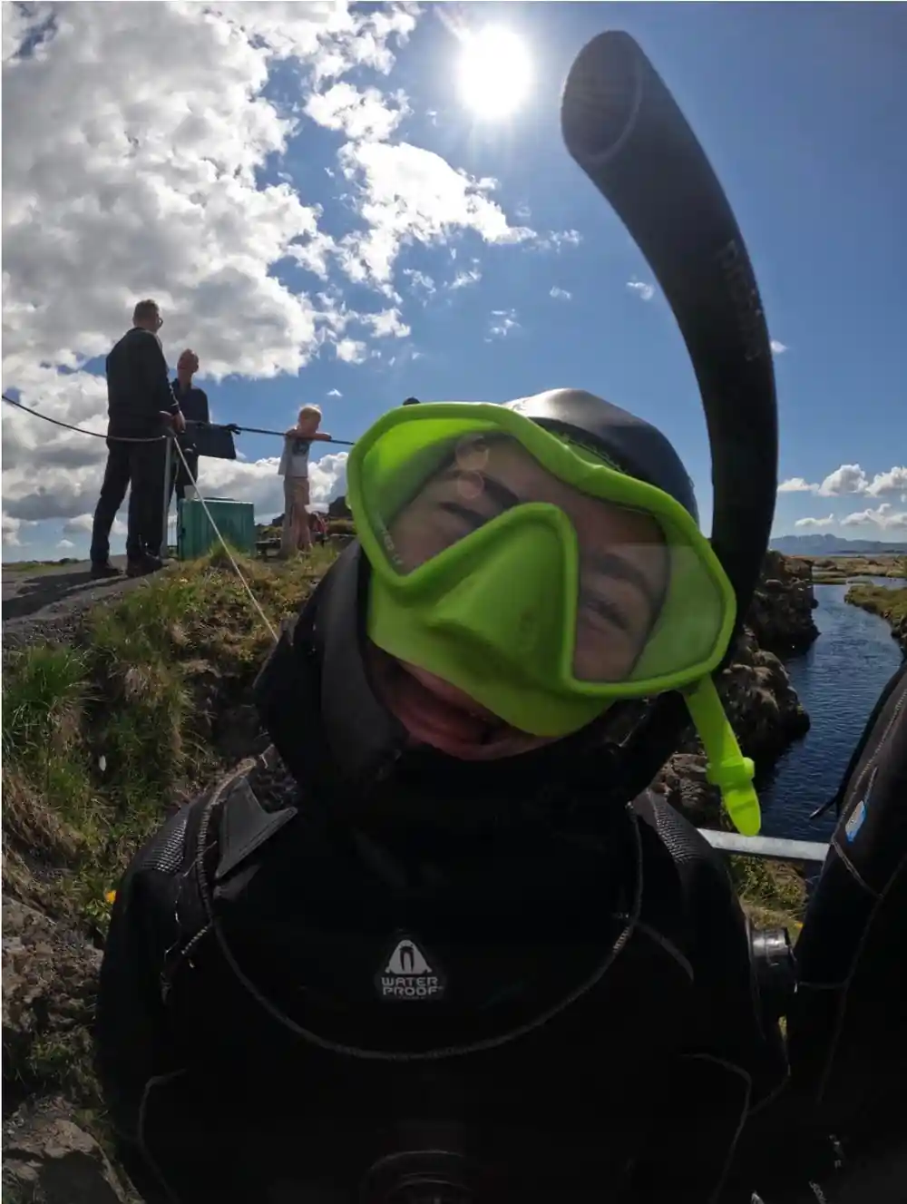Diver in yellow mask on grassy bank with others watching