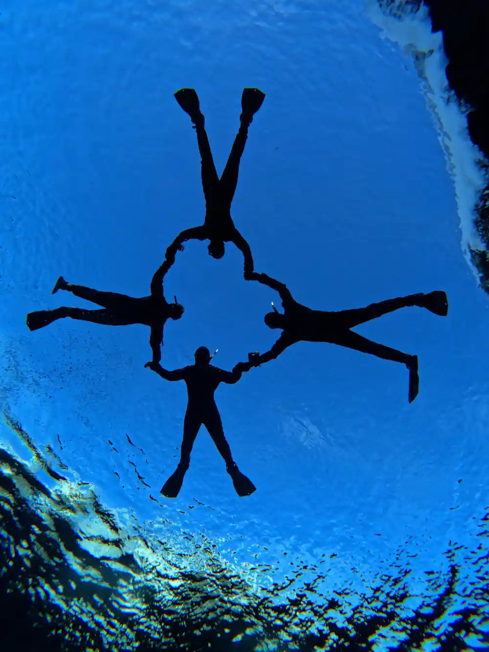 Divers swimming in bright blue underwater canyon passageway