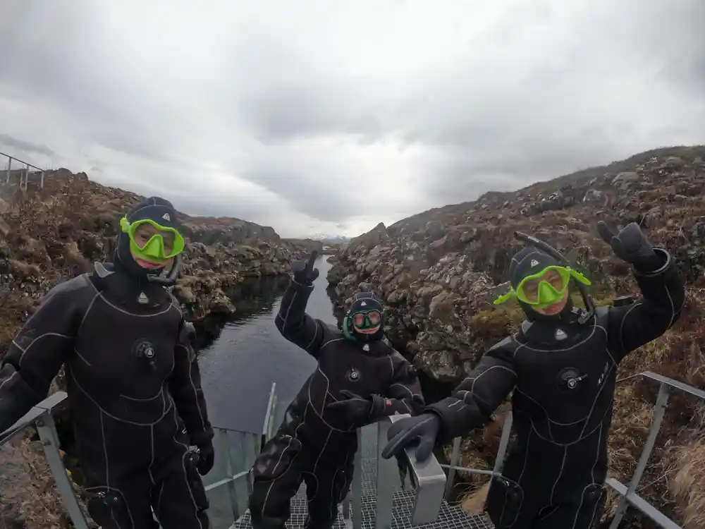 Four divers in wetsuits on platform above rocky canyon