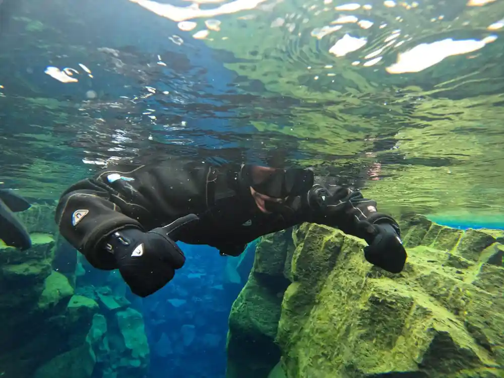 Scuba diver in black wetsuit near underwater rock formations