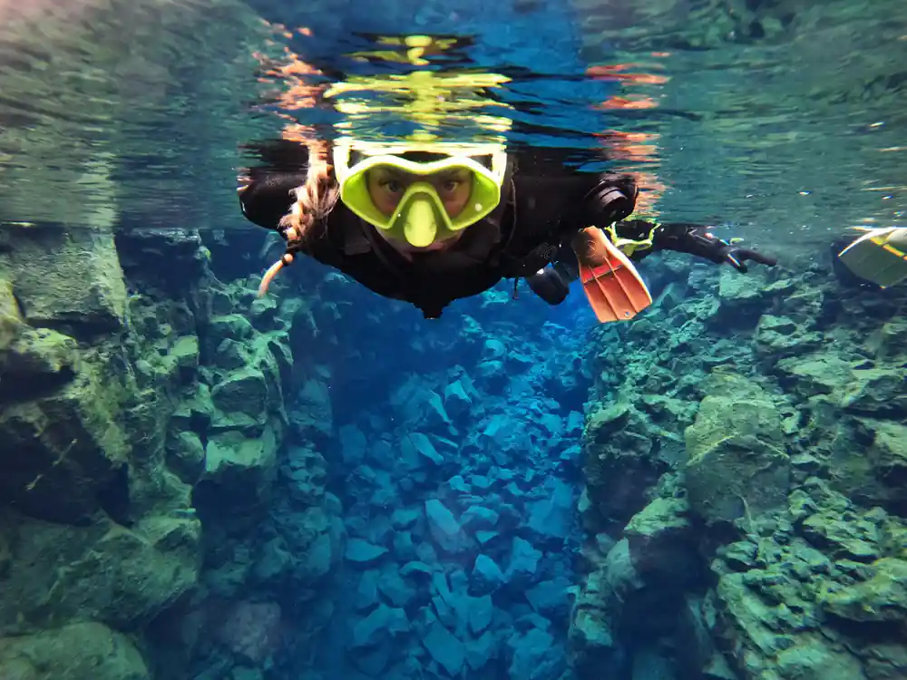 Single diver in bright mask facing camera in underwater crevasse
