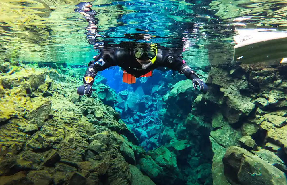 Snorkelers swimming above rocky underwater formations