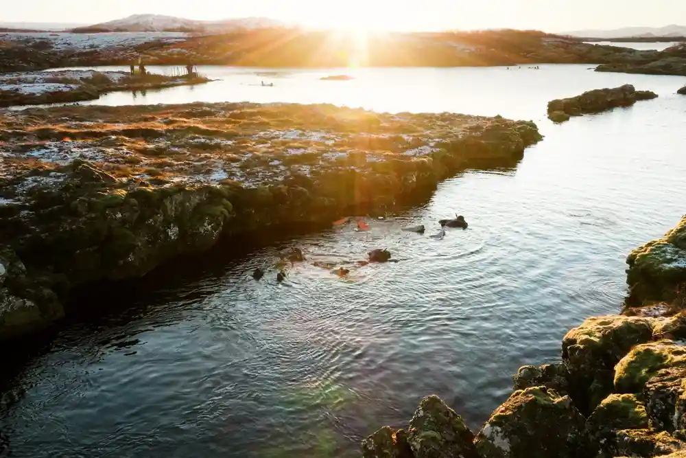Sunset over landscape with water, rocks and distant mountains