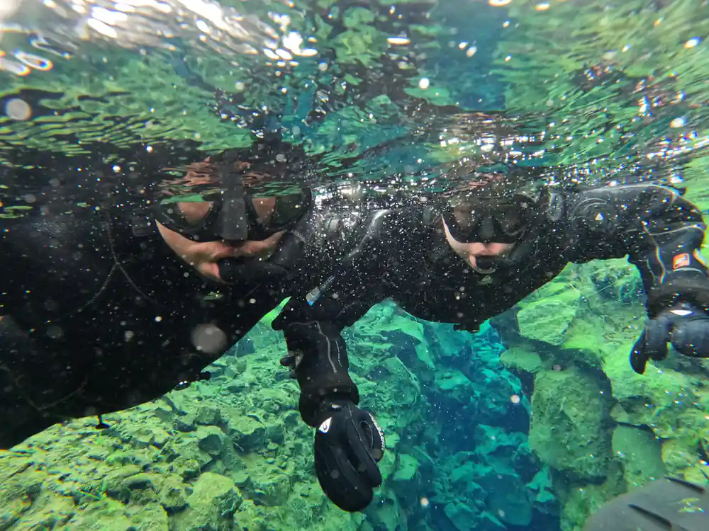 Two snorkelers in water showing thumbs up gestures