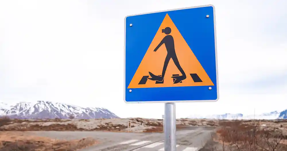 Yellow warning sign with pedestrian slipping symbol